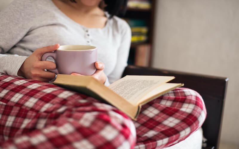 Tee trinken und Buch lesen