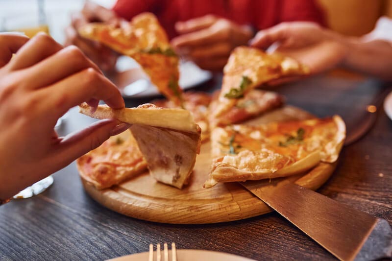 Menschen essen gemeinsam Pizza während der Vorbereitungstage