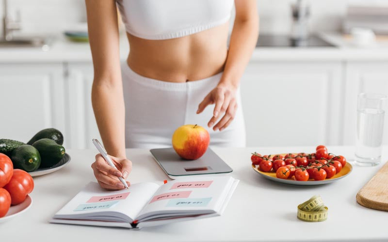 Frau wiegt ihr essen ab und zählt die Kalorien während der Stoffwechselkur