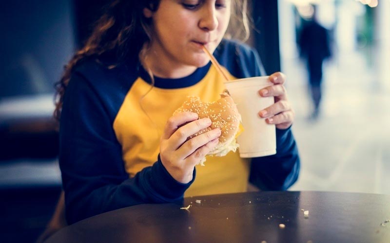 Zu Übergewicht neigende Frau isst ungesunde Mahlzheit