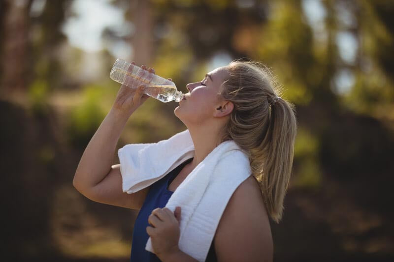 Junge Frau trinkt nachdem Laufen Wasser